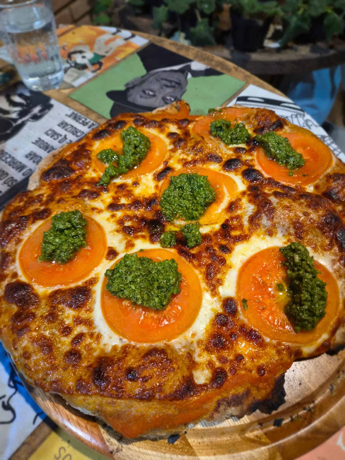 Pizza com tomate e pesto servida na tábua de madeira